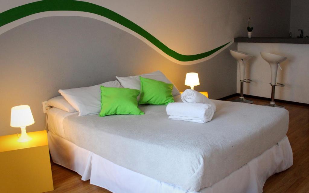 a bedroom with a bed with green and white pillows at Che Lagarto Hostel Montevideo in Montevideo