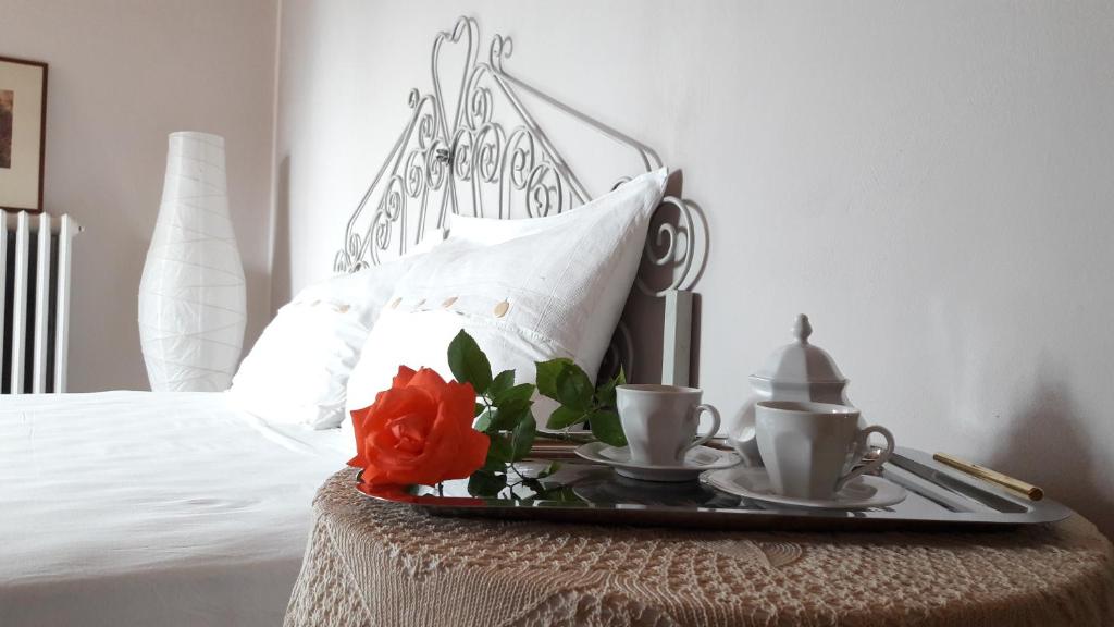 a tray with two cups and two roses on a bed at Chalet nelle vigne in Novello