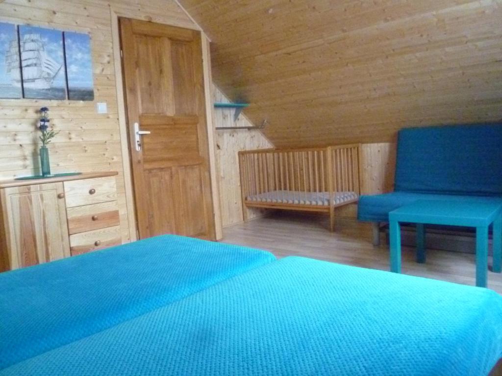 a bedroom with a blue bed and a blue chair at Tęczowe Domki in Władysławowo
