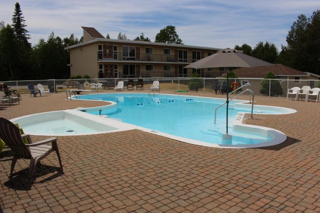 a large swimming pool with an umbrella and a building at Sauble Beach Lodge in Sauble Beach