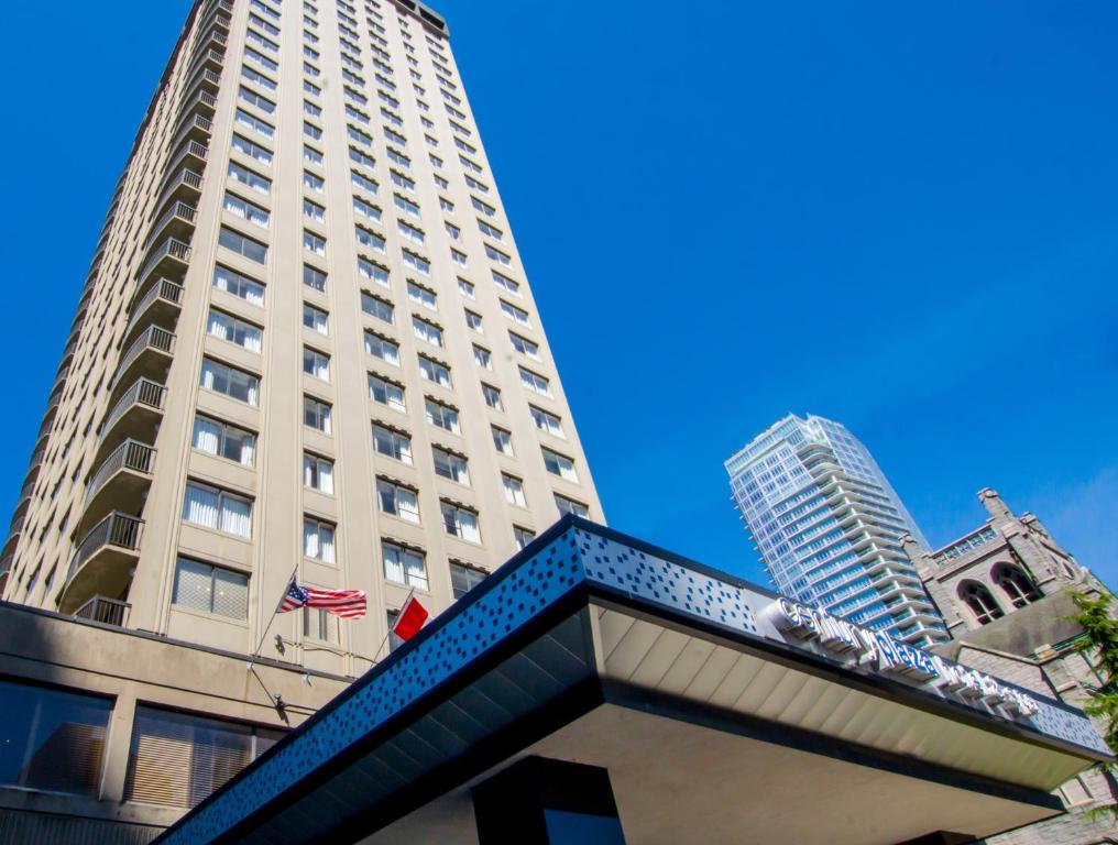 溫哥華的住宿－Century Plaza Hotel，前面有旗帜的高大的白色建筑