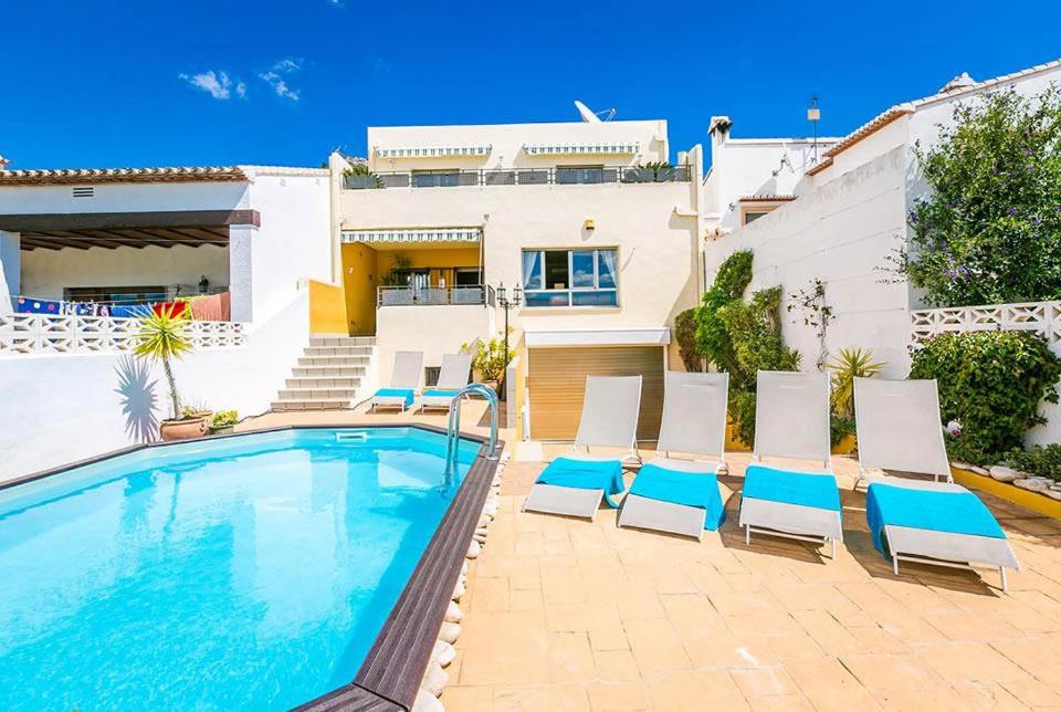 a swimming pool with chairs and a house at Fully Airconditioned Costa Blanca Pool House with Superb Views Over the Orba Valley, Sleeps 12 in Benimeli