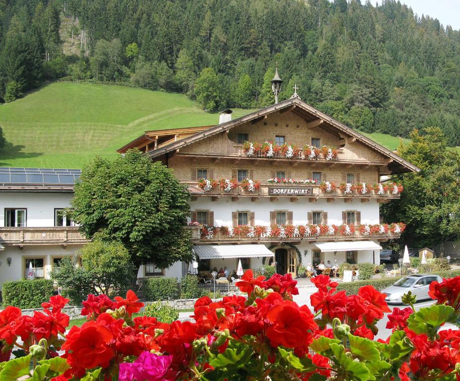 ein großes Gebäude mit roten Blumen davor in der Unterkunft Landgasthof Dorferwirt in Oberau