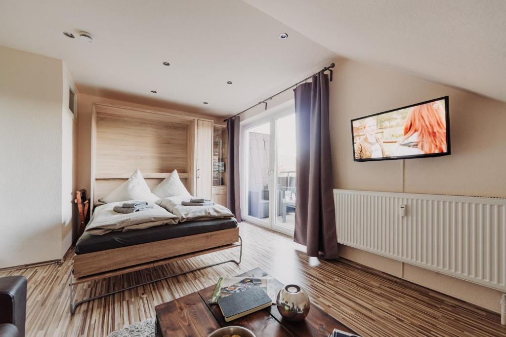 1 dormitorio con 1 cama y TV en la pared en Hexe I - mit Blick auf den Wurmberg, en Braunlage