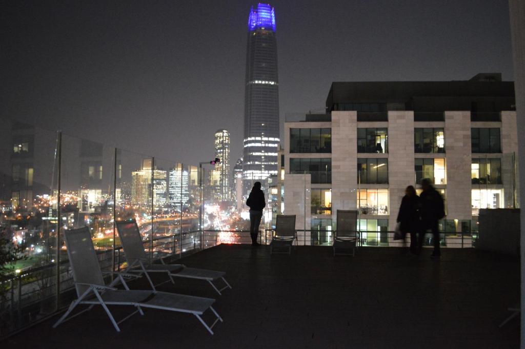 un grupo de personas de pie en la parte superior de un edificio por la noche en Apart Lyon Suite, en Santiago
