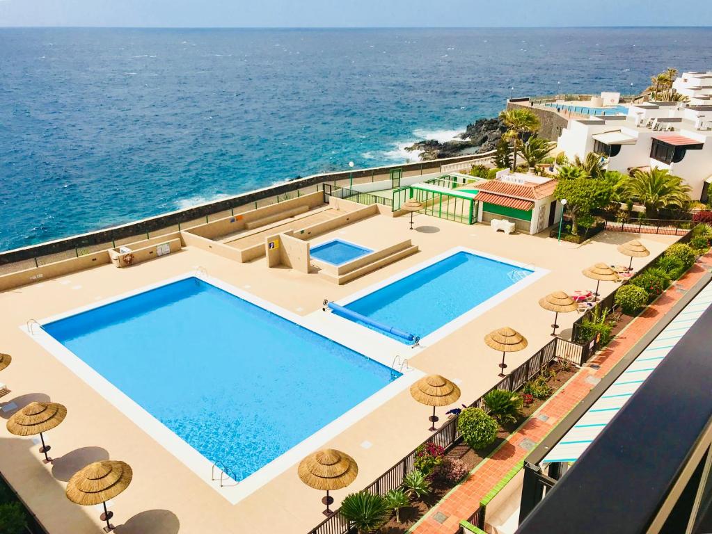 an aerial view of a swimming pool with the ocean at Atlantic View - quiet, peaceful and windless apt with fantastic ocean view in Costa Del Silencio