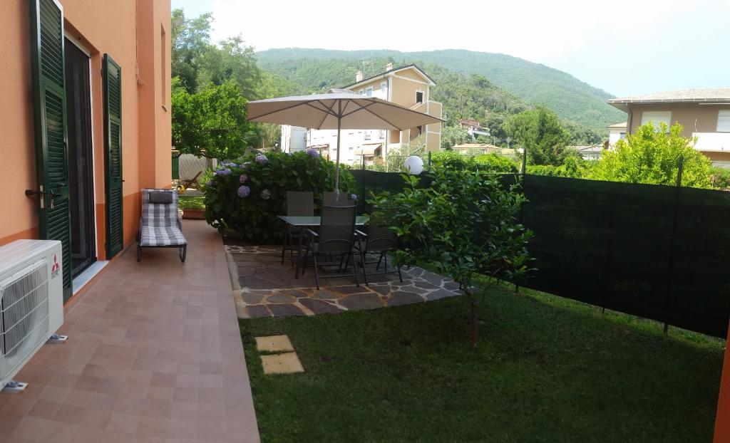 a patio with a table and chairs and an umbrella at Appartamento Tramontana in Deiva Marina