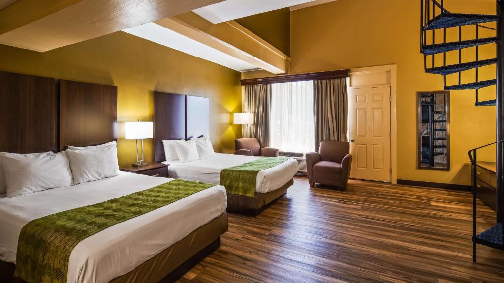a hotel room with two beds and a chair at Best Western Plaza Inn in Pigeon Forge