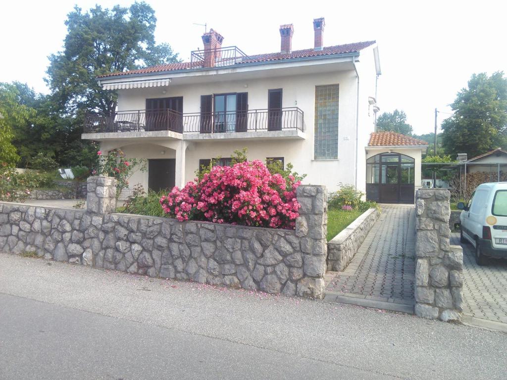 a white house with a stone wall and flowers at Viki in Kastav