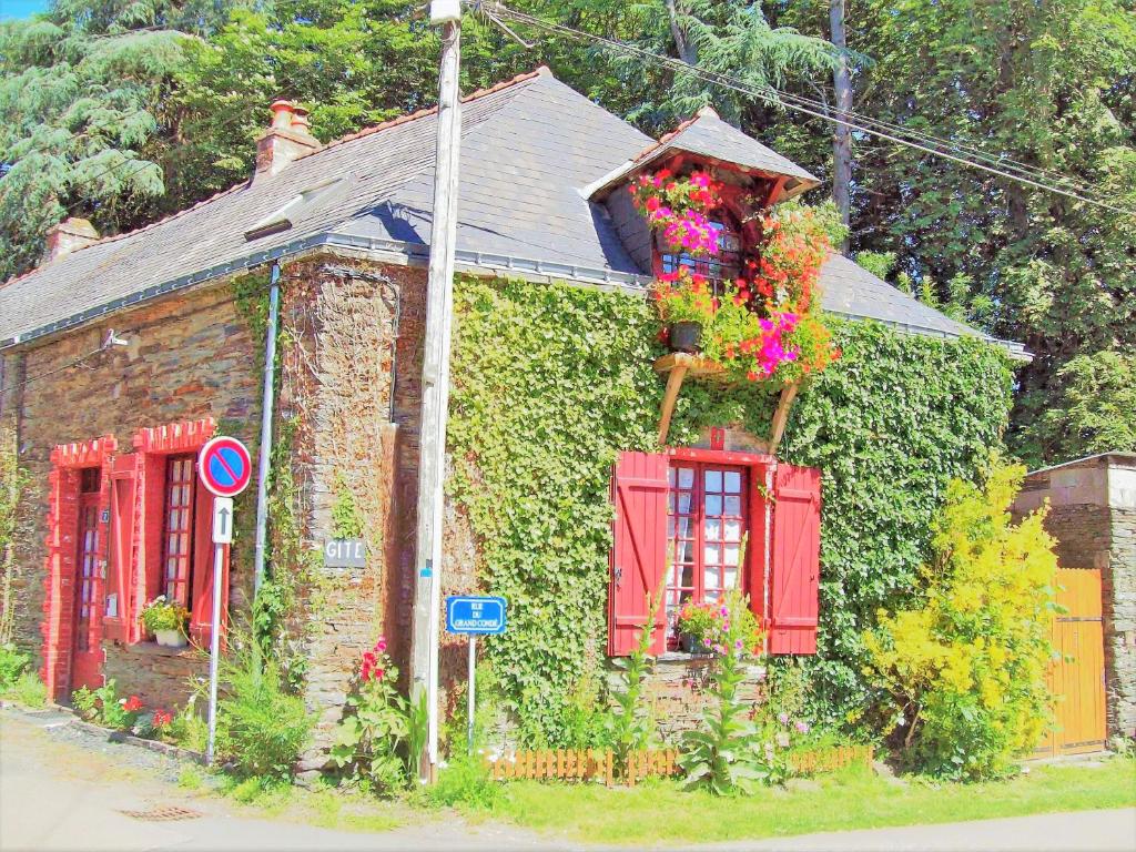 ein altes Backsteinhaus mit roten Fenstern und Efeu in der Unterkunft Gîte du fourneau in La Forge-Neuve