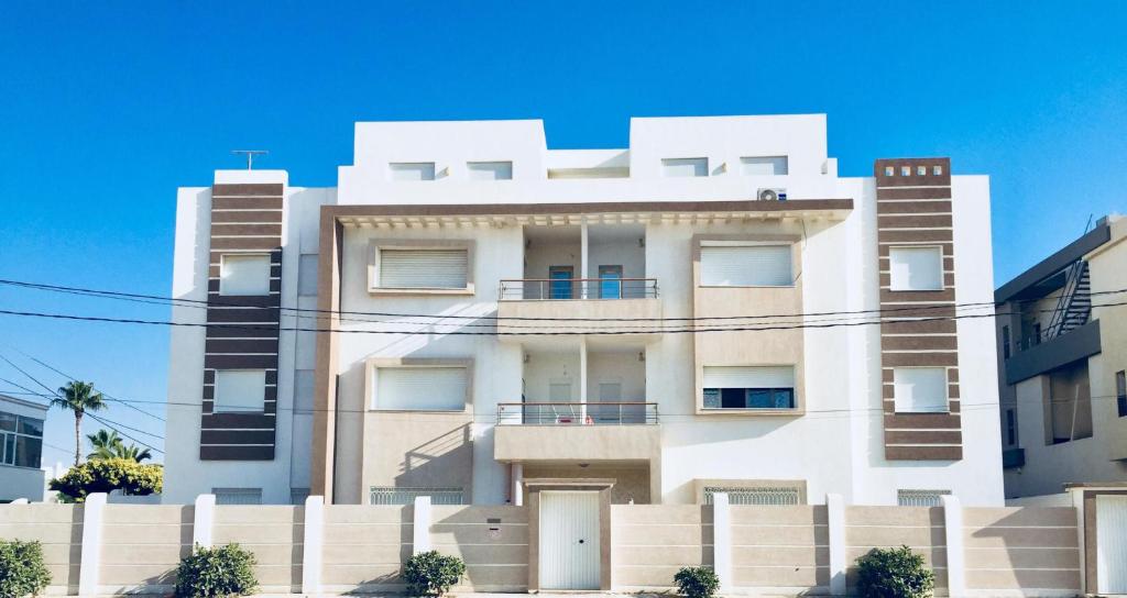 Ein weißes Gebäude mit einem Zaun davor. in der Unterkunft Altavista Appartment in Sousse