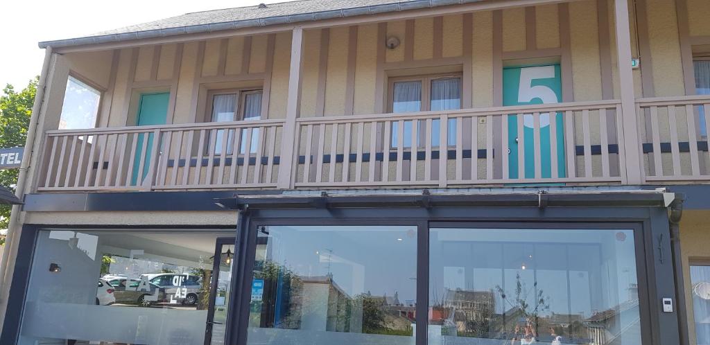 a building with a balcony on top of it at Hôtel L'ideal le Mountbatten in Arromanches-les-Bains