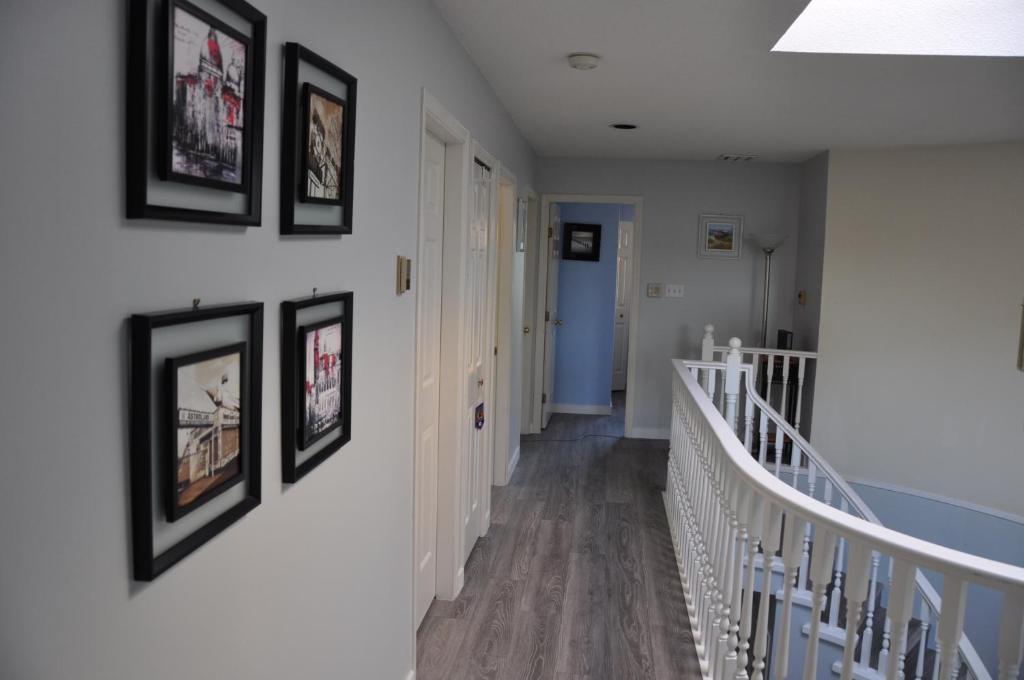 a hallway with a staircase with framed pictures on the walls at Better Bed in Richmond