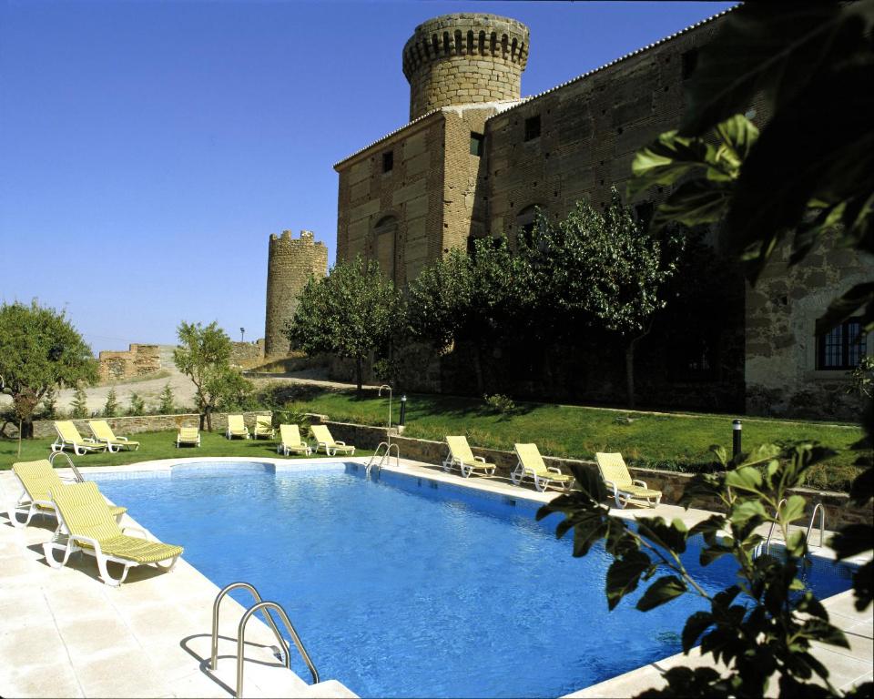 a large swimming pool in a garden area at Parador de Oropesa in Oropesa