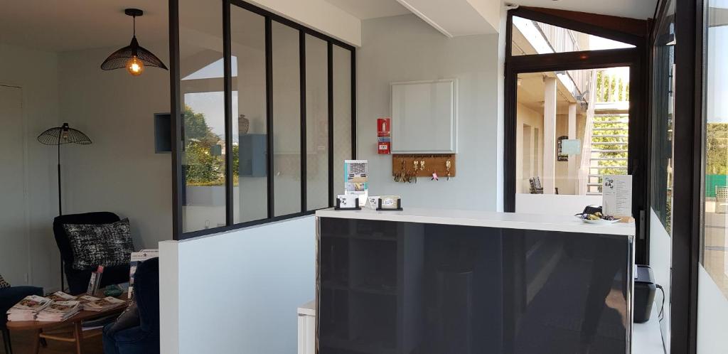 a kitchen with a white counter and a window at Hôtel L'ideal le Mountbatten in Arromanches-les-Bains