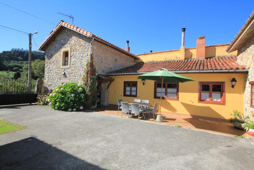 a yellow house with a table and an umbrella at La Llosa II in Villaviciosa
