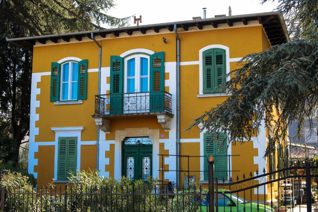 un edificio amarillo y verde con persianas verdes en apartman Cedra, en Izola