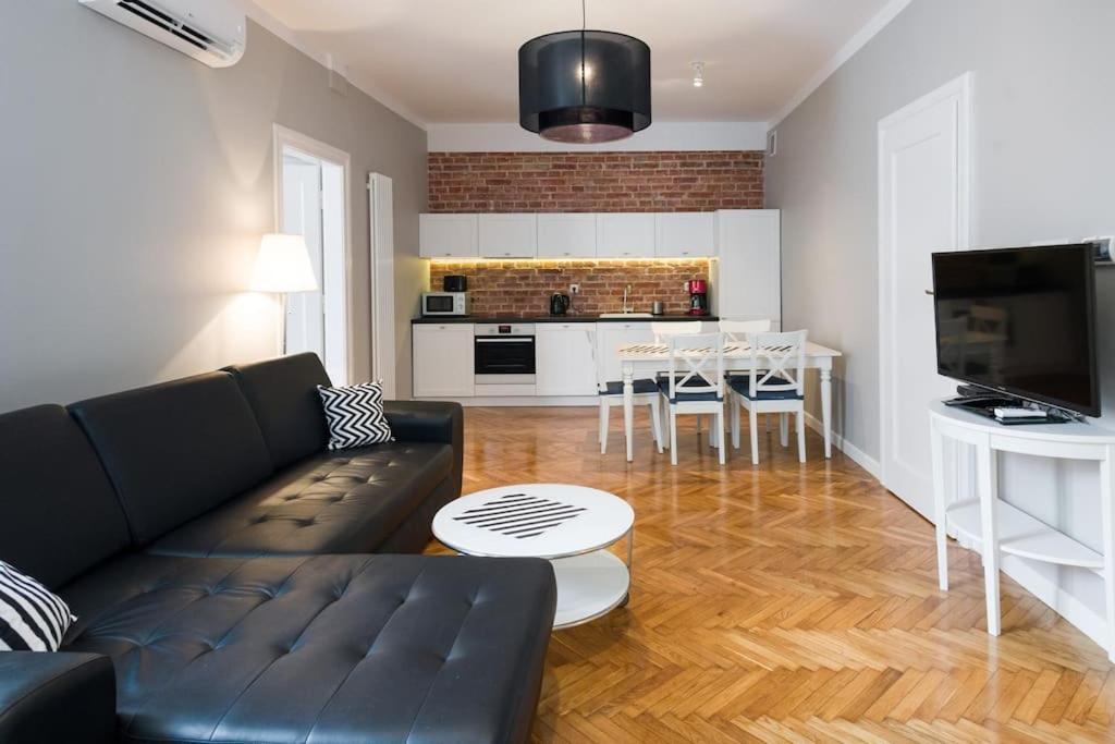 クラクフにあるFlorianska Deluxe Apartments with Air Conditionのリビングルーム(黒いソファ付)、キッチン