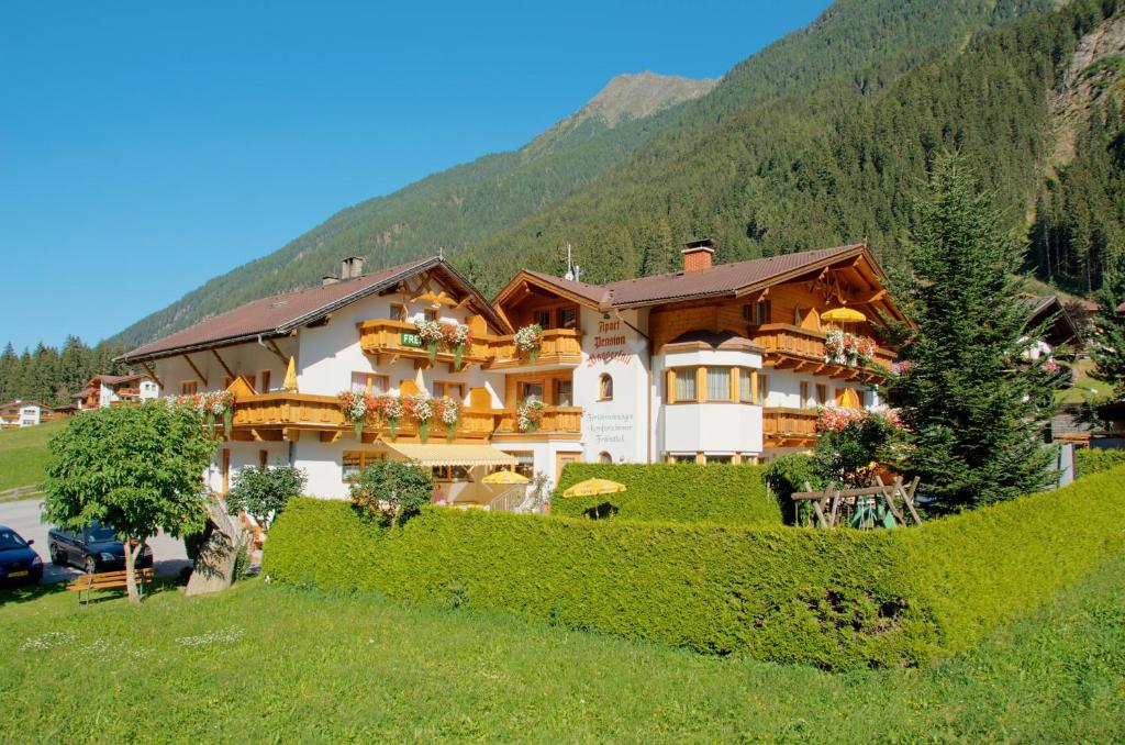 a large building on a hill with a mountain at Apart-Pension Wasserfall in Neustift im Stubaital