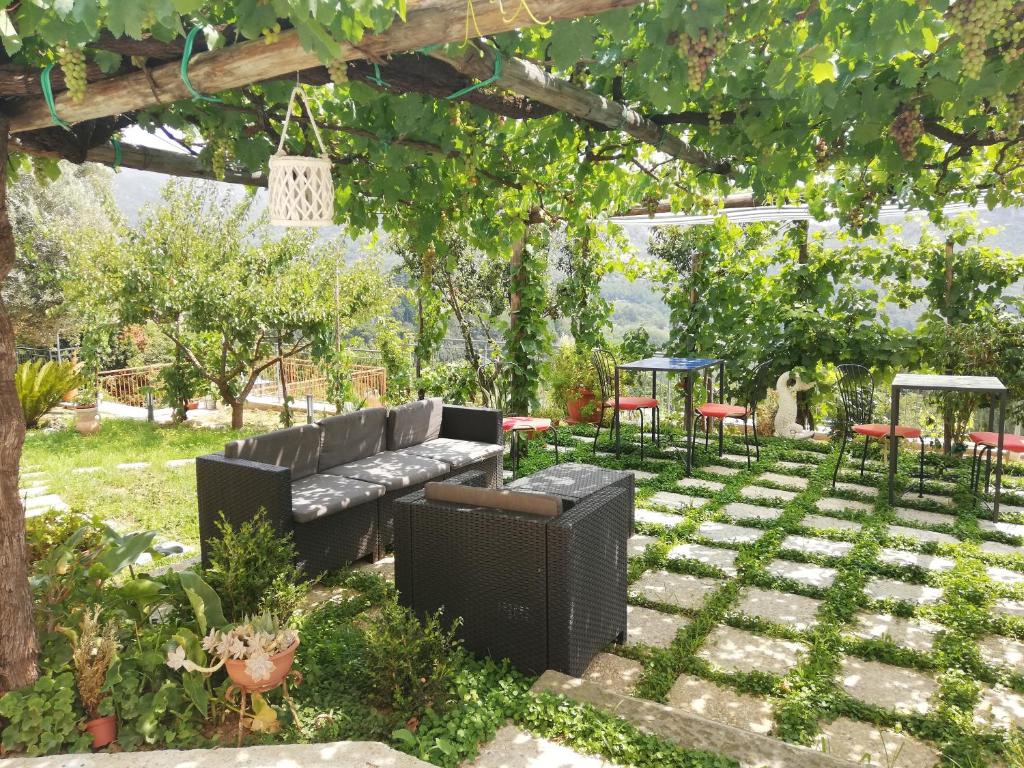 a garden with a black couch and chairs under a pergola at La Roccia Incantata Amalfi Coast in Vietri sul Mare