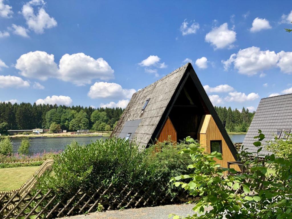 ein Haus mit einem Strohdach neben einem See in der Unterkunft Wooden chalet with oven, in Oberharz near a lake in Clausthal-Zellerfeld