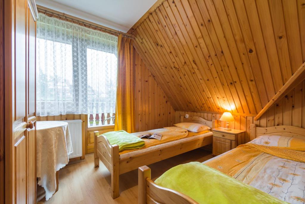 two beds in a room with wooden walls at Pokoje u Bobików in Ząb