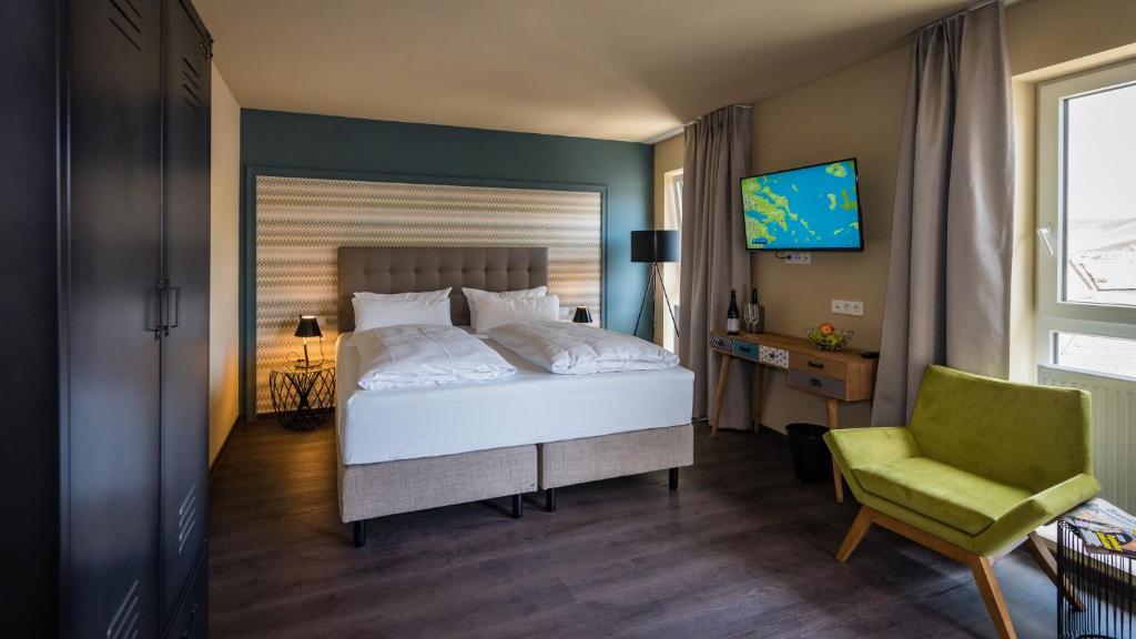 1 dormitorio con 1 cama, 1 silla y TV en Hotel Goldene Traube - by Neugart en Traben-Trarbach