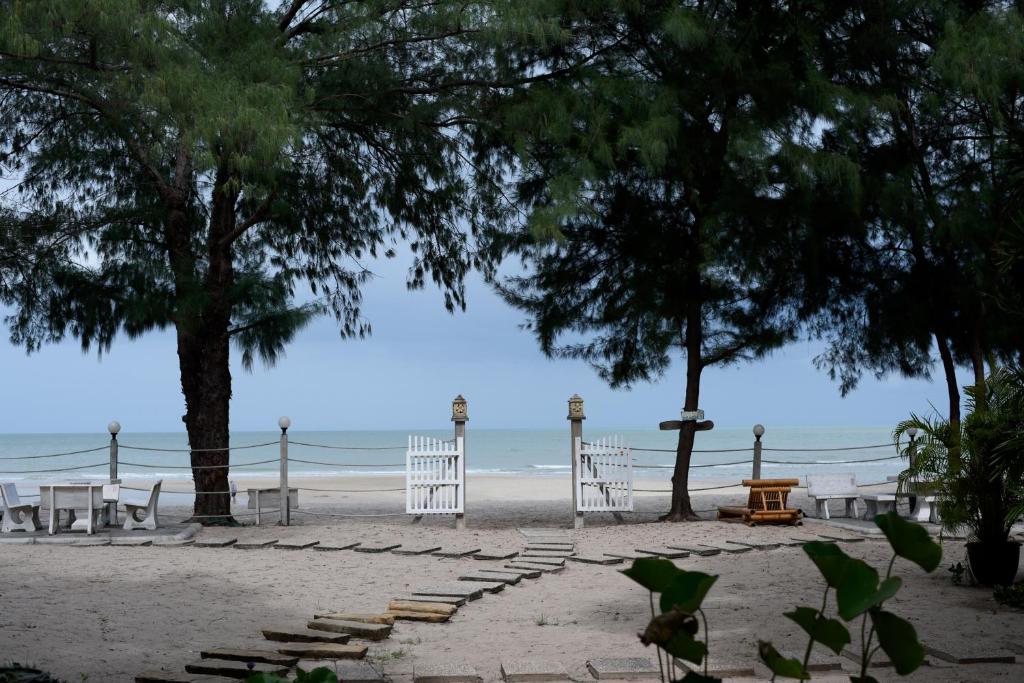 a beach with two trees and stairs on the beach at Baan Kratom Tong by the sea in Cha Am