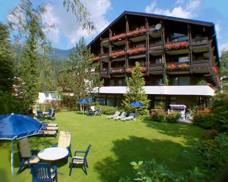 a large building with a yard with chairs and tables at Appartementhaus Gastein inklusive Alpentherme gratis in Bad Hofgastein