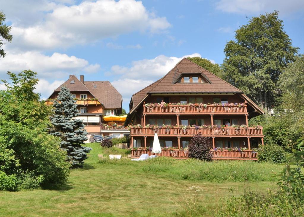 a large house with a large deck in a yard at IMbery Hotel & Restaurant Hinterzarten in Hinterzarten