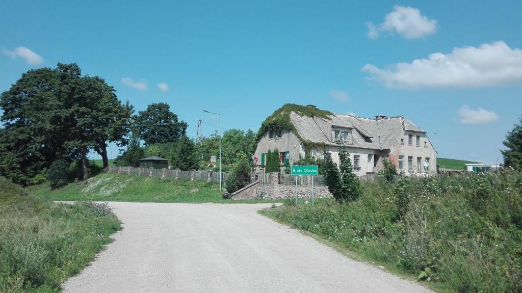 ein altes Haus am Straßenrand in der Unterkunft Nad stawem in Biała Olecka