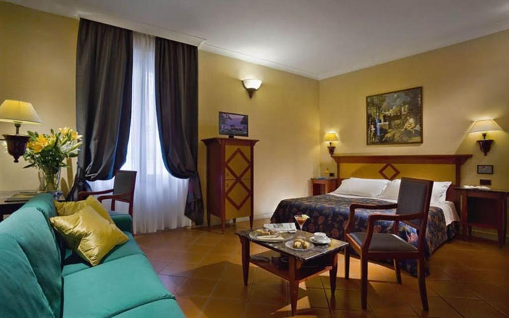 フィレンツェにあるコロナ ディタリアのソファ、ベッド、テーブルが備わるホテルルームです。