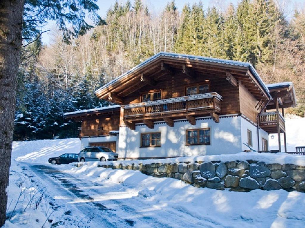 una cabaña de madera en la nieve con un coche aparcado delante en Ferienwohnung Steiner, en Wald im Pinzgau