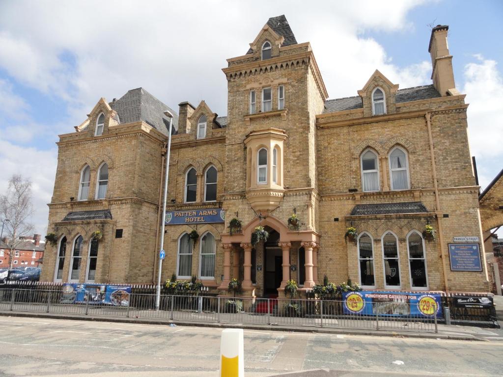 a large brick building with a fence in front of it at Patten Arms Hotel in Warrington