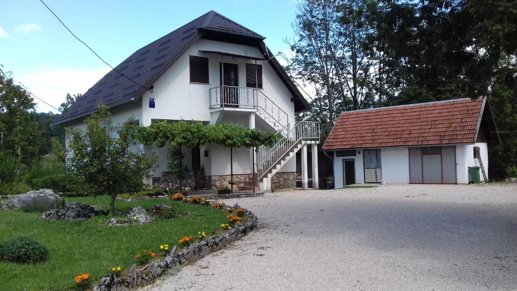 a white house with a red roof and a yard at House Luketić in Rastovača