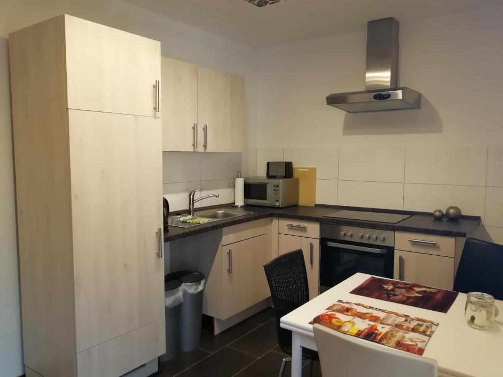 a kitchen with white cabinets and a table and a sink at Apartment am Park - Erica in Schneverdingen