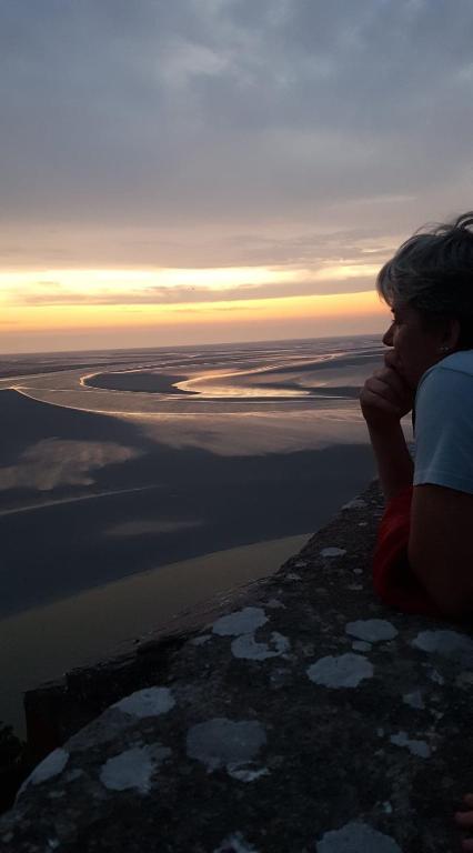 une femme assise sur une falaise en regardant le coucher du soleil dans l'établissement L'étoile CarVal, à Sains