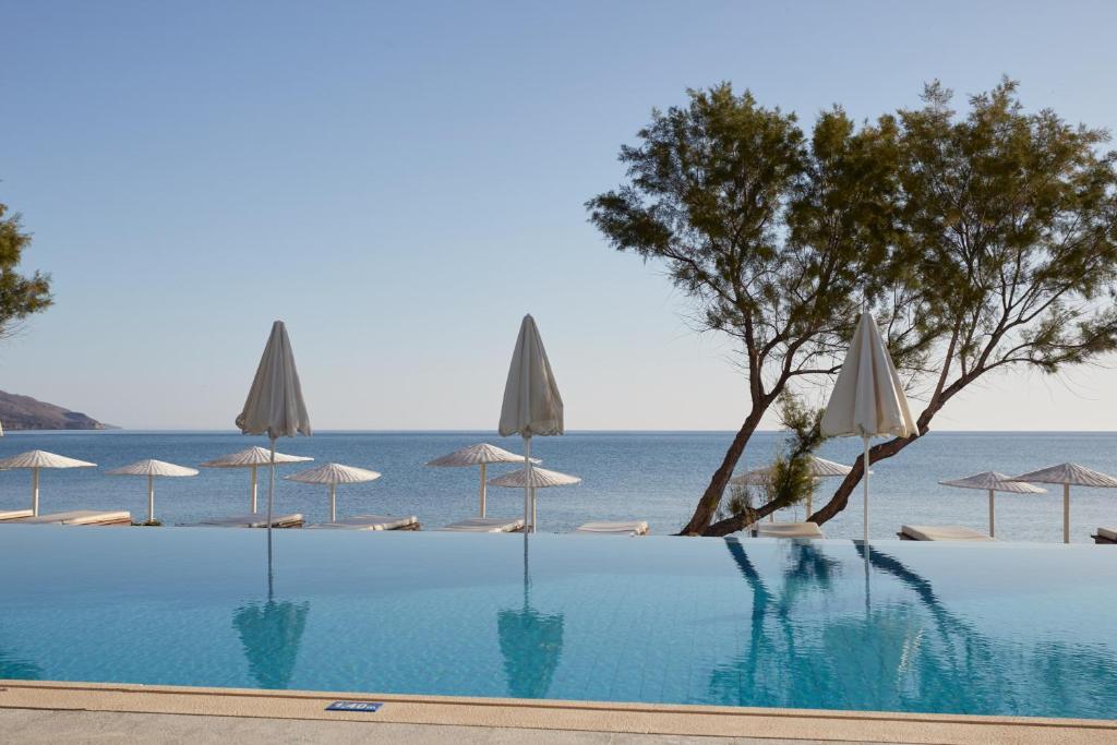 a swimming pool with umbrellas and the ocean at Giannoulis - Grand Bay Beach Resort (Exclusive Adults Only) in Kolymvari