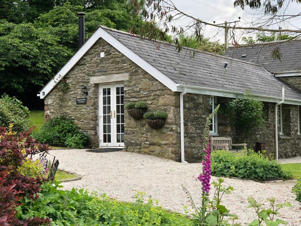 a stone cottage with a bench in a garden at Almond Tree Cottage in Lanteglos