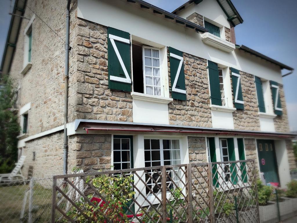 TreignacにあるMaison Raffineeの緑窓と柵のある石造りの家