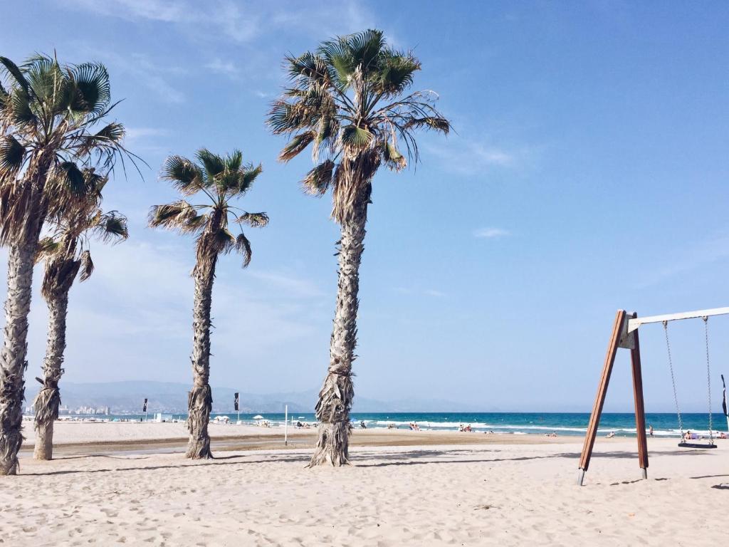 a group of palm trees on a beach with a swing at New apartment in San Juan Playa, Alicante in Alicante