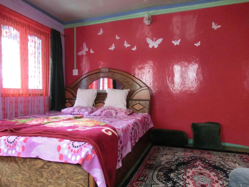 - une chambre dotée d'un lit avec un mur rouge aux papillons dans l'établissement Homestay Hari Parbat, à Srinagar