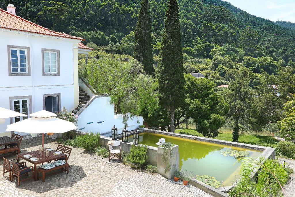 a house with a swimming pool and a table and chairs at Eugaria Country House by Lost Lisbon in Sintra