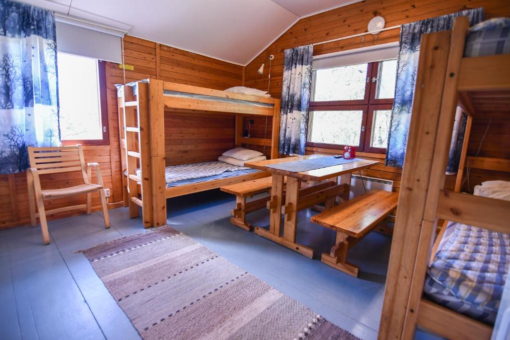 a room with bunk beds and a table and a desk at Kilpisjärven Retkeilykeskus Cottages in Kilpisjärvi