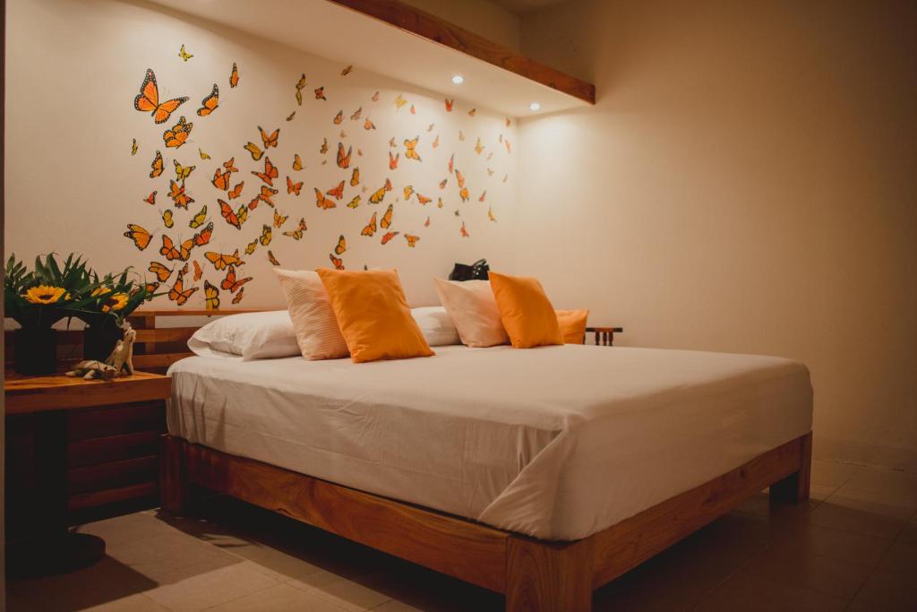 a bedroom with a bed with butterflies on the wall at Casa 5 Bed & Breakfast in Palenque