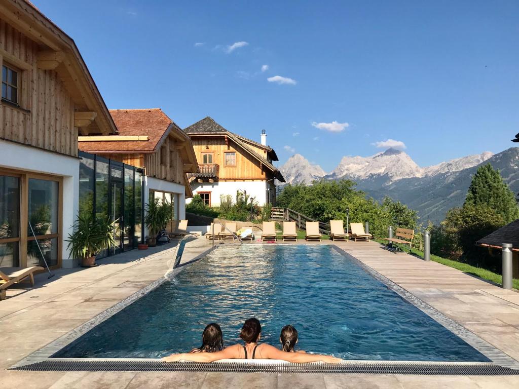 zwei Frauen in einem Schwimmbad mit Bergen im Hintergrund in der Unterkunft Almresort Baumschlagerberg in Vorderstoder