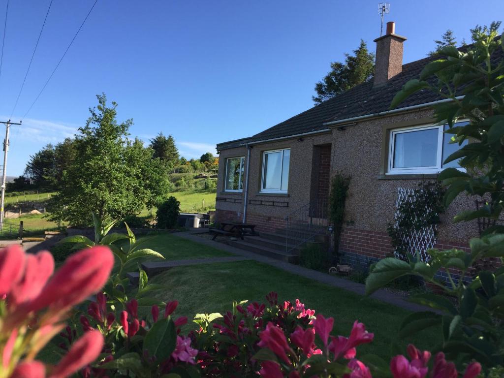 a house with a yard with flowers in front of it at The Sheiling B&B - NC 500 in Melvich