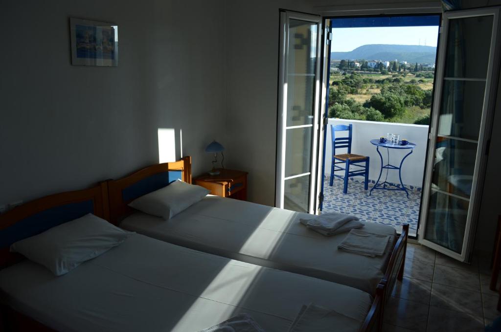 a bedroom with two beds and a balcony with a table at Theofilos Appartements in Livadi