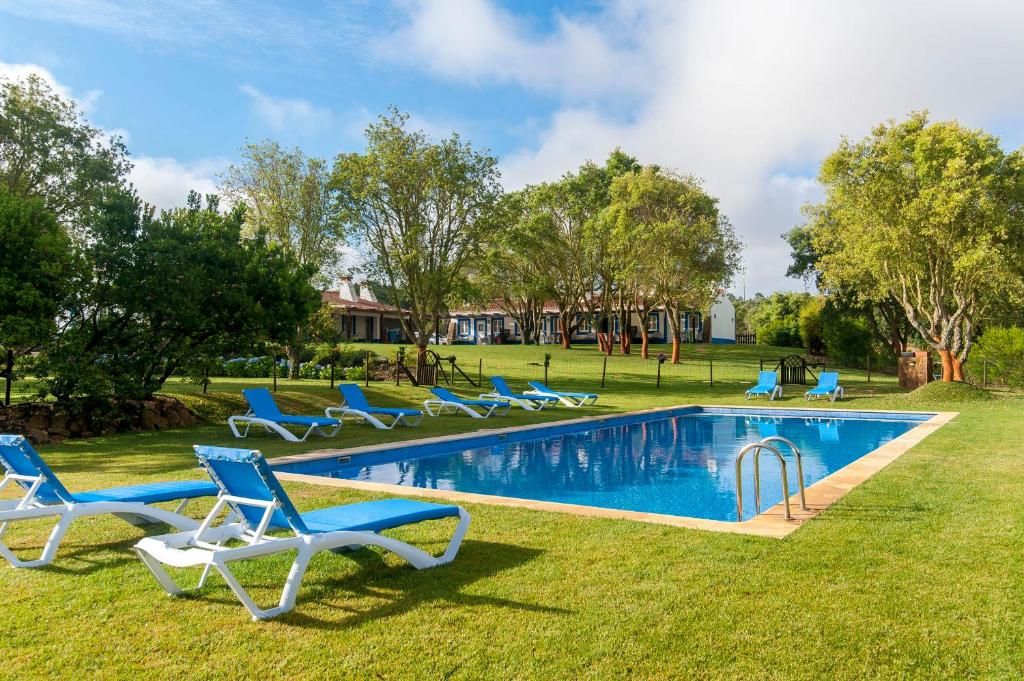 uma piscina com espreguiçadeiras num quintal em Monte Da Galrixa em Zambujeira do Mar