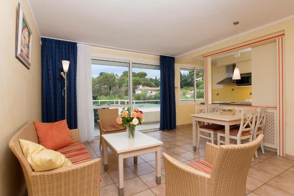 a living room with a table and chairs and a kitchen at Résidence les Tourelles in Sainte-Maxime